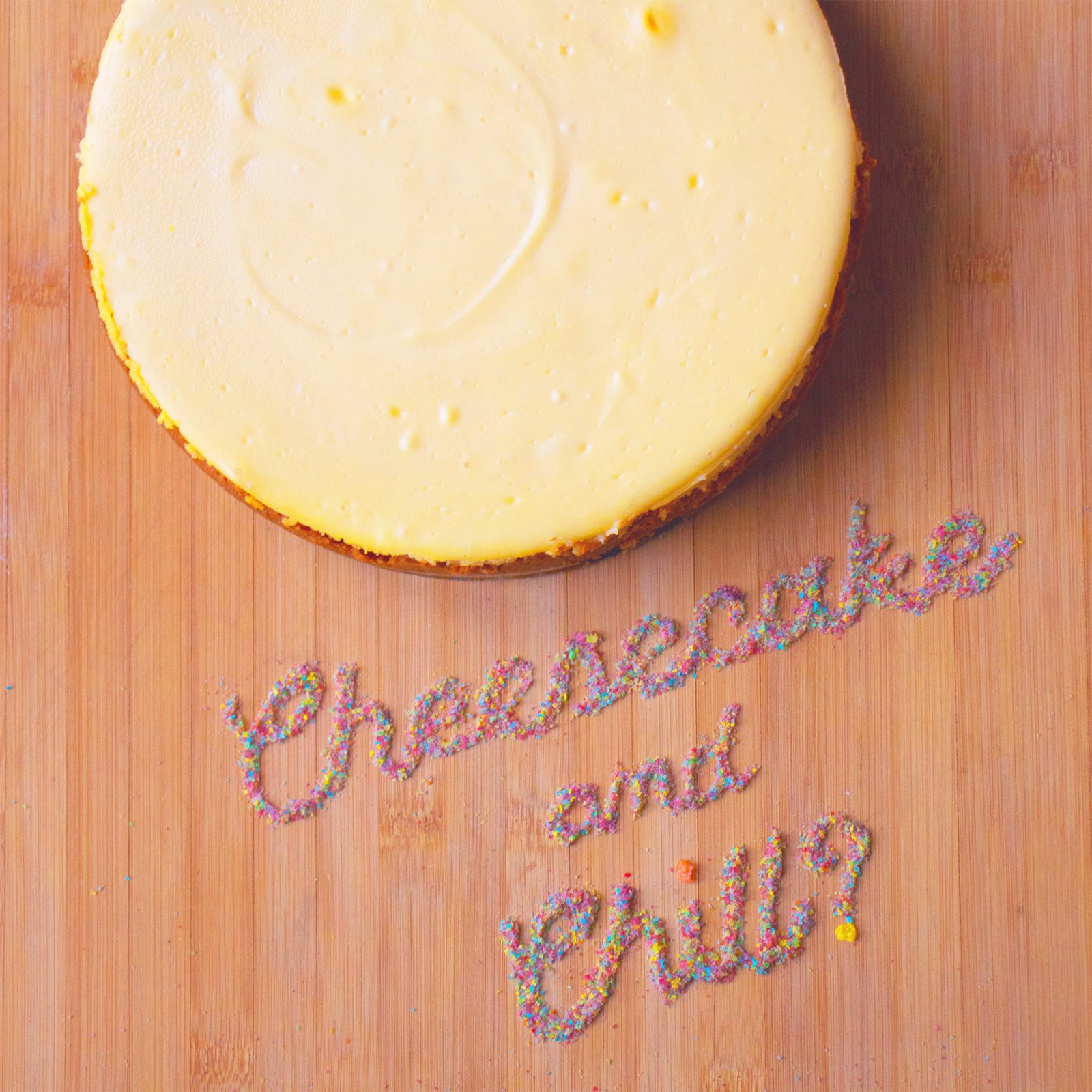 Photograph of an American-style cheesecake, with the words, “Cheesecake and Chill” written in Fruity Pebbles cereal.