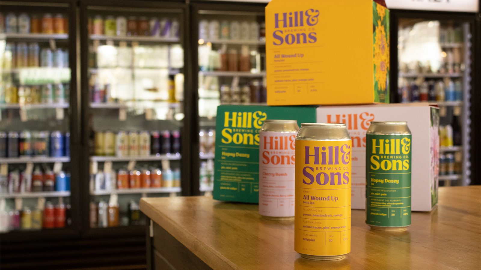 Brightly coloured beer cans and boxes sit on a sunny counter.