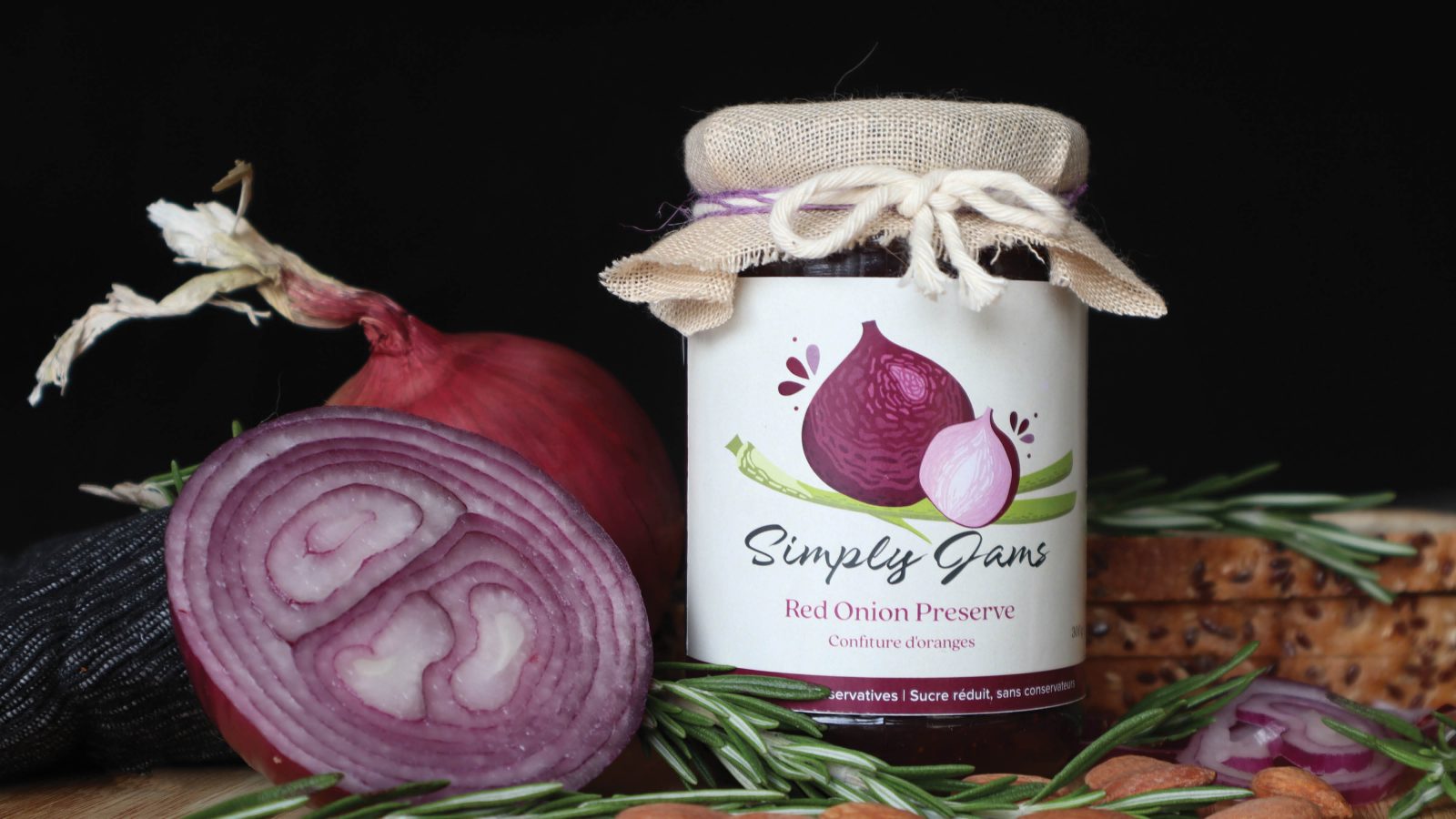 Simply Jams represents the classic taste of home cooking, using simple ingredients to capture the essence of traditional recipes. The Onion Reserve variety is presented in a jar with a rich purple color, surrounded by fresh onions.